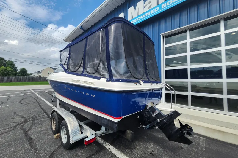 Slide: The Image of 2017 Bayliner 210 Cuddy boat on trailer, parked outside a marine dealership. - 3