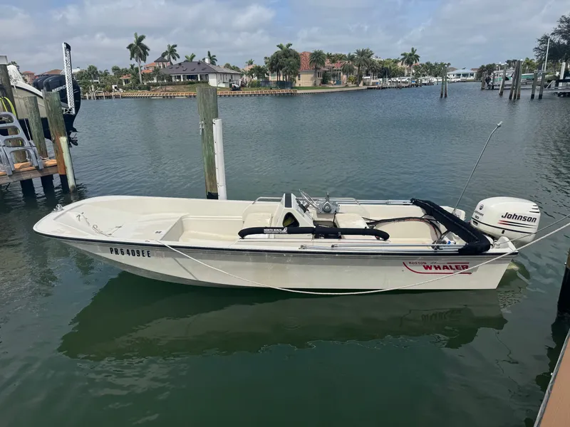 The Image of A 1993 Boston Whaler 17 Sport GLS is docked on the water. Palm trees in the background. - 0