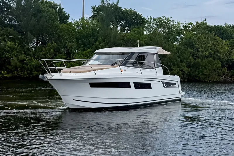 Slide: The Image of 2016 Jeanneau Merry Fisher 855 cruising on a calm river with lush greenery. - 2