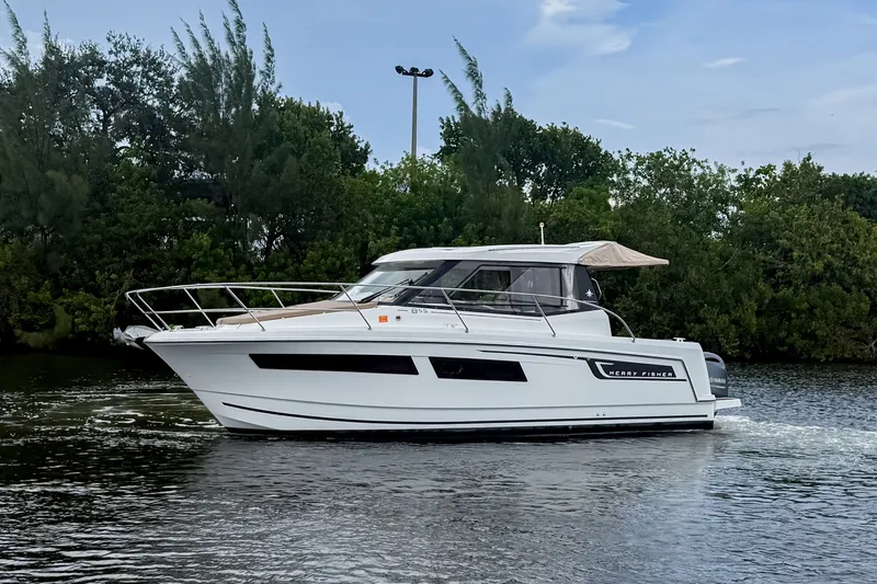 The Image of 2016 Jeanneau Merry Fisher 855 cruising on a calm river with lush greenery. - 0