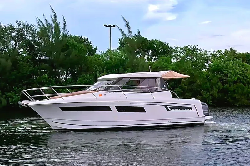 The Image of A 2016 Jeanneau Merry Fisher 855 cruising on calm waters, surrounded by trees. - 0