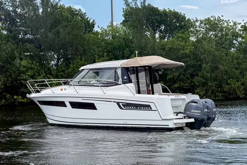 Slide: The Image of 2016 Jeanneau Merry Fisher 855 boat cruising on a calm river with lush greenery. - 4