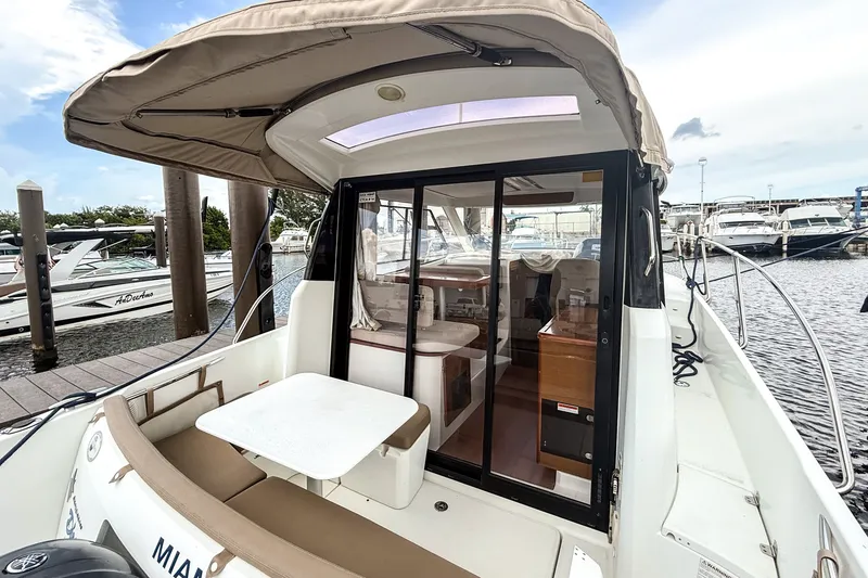 Slide: The Image of 2016 Jeanneau Merry Fisher 855 boat docked, featuring a covered seating area and sliding glass doors. - 10