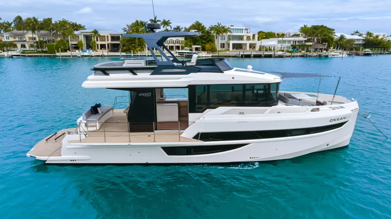 Slide: The Image of The 2027 OKEAN 52 is a sleek motor yacht with a modern design, floating on calm waters. - 16