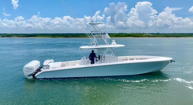 Slide: The Image of A sleek white boat with three outboard engines cruises on calm water under a clear sky. - 21