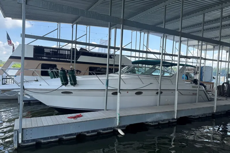 The Image of 1994 Regal Commodore 400 boat docked in a marina under a covered structure. - 0