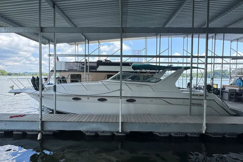 Slide: The Image of 1994 Regal Commodore 400 yacht docked under a covered marina with scenic lake view. - 3