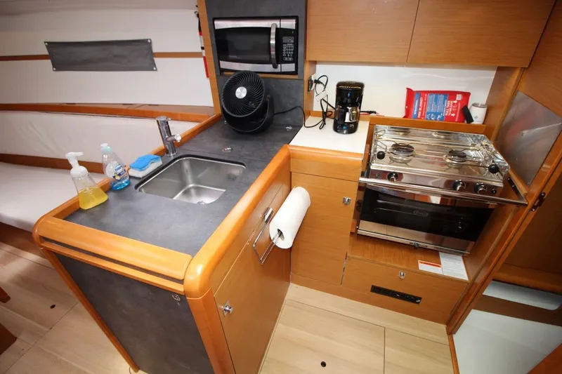 Slide: The Image of Compact kitchen in 2015 Jeanneau Sun Odyssey 349 yacht with stove, sink, and microwave. - 22