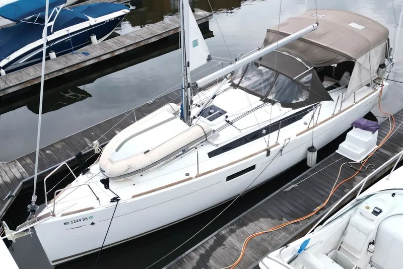 Slide: The Image of 2015 Jeanneau Sun Odyssey 349 sailboat docked at marina, featuring sleek design and canopy. - 11