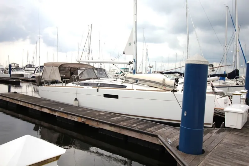 The Image of 2015 Jeanneau Sun Odyssey 349 sailboat docked at marina under cloudy sky. - 2