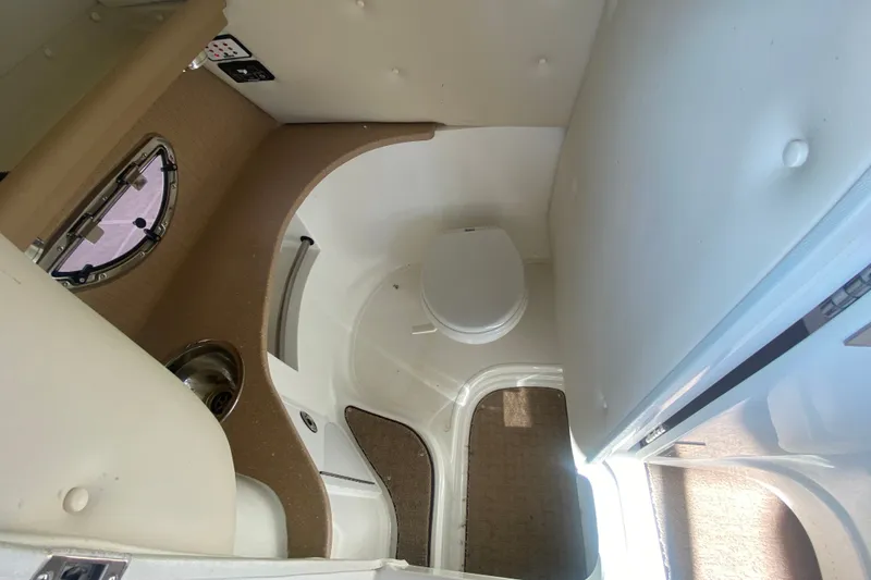 Slide: The Image of Interior of a 2010 Cobalt 302 boat featuring a compact bathroom with a toilet and sink. - 28