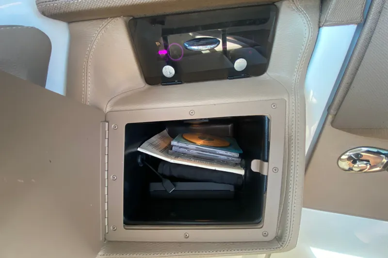 Slide: The Image of Open storage compartment in a 2010 Cobalt 302 boat, containing CDs and documents. - 27