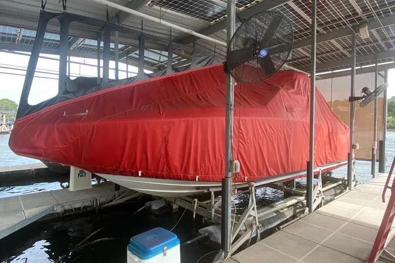 Slide: The Image of 2010 Cobalt 302 boat covered in red tarp on a dock lift. - 38