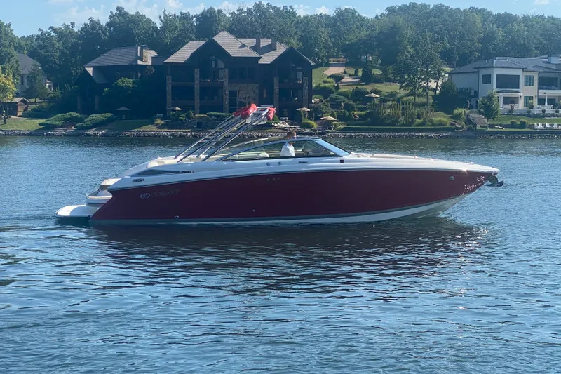 Slide: The Image of 2010 Cobalt 302 boat cruising on a serene lake with luxury homes in the background. - 2