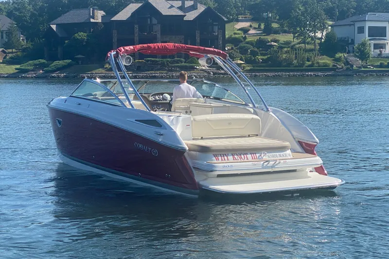 Slide: The Image of 2010 Cobalt 302 boat cruising on a serene lake near luxury homes. - 6