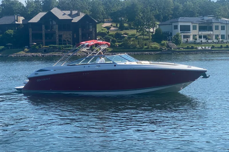 Slide: The Image of 2010 Cobalt 302 boat cruising on a serene lake near luxury homes. - 3