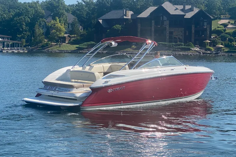 Slide: The Image of 2010 Cobalt 302 boat on a serene lake with lush greenery and houses in the background. - 9