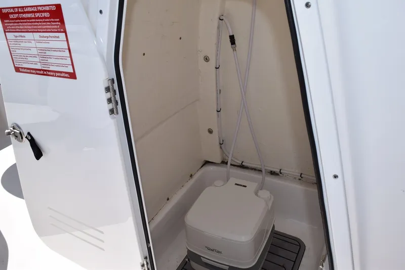 Slide: The Image of 2023 Tidewater 232 SS boat interior with portable toilet and storage compartment. - 16