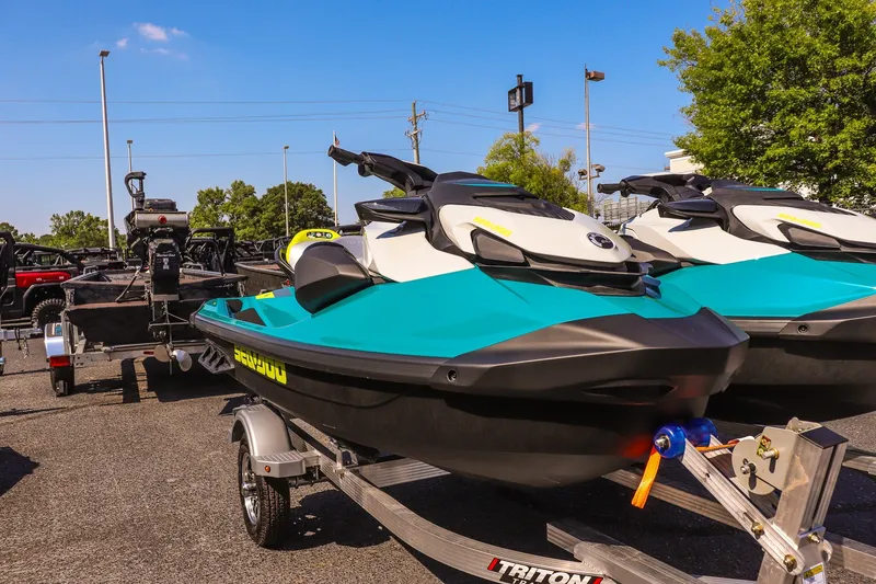 The Image of 2026 Sea-Doo GTI SE 170 jet skis on trailers, parked outdoors under a clear blue sky. - 1
