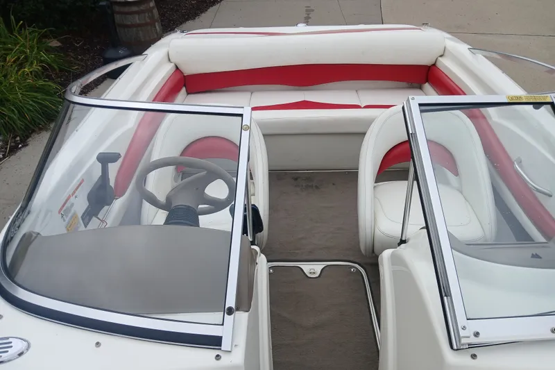 Slide: The Image of 2003 Larson SEi 180 boat interior with red and white seating and dual windshields. - 11