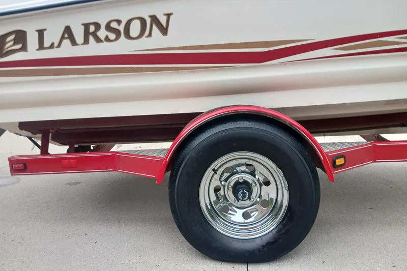 Slide: The Image of 2003 Larson SEi 180 boat on red trailer, showcasing wheel and side design. - 6
