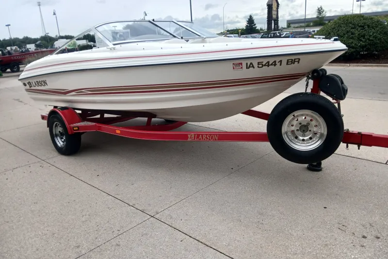 Slide: The Image of 2003 Larson SEi 180 boat on red trailer, parked outdoors. - 4