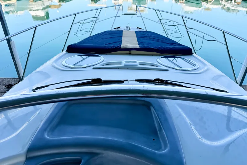 Slide: The Image of 2005 Cranchi Endurance 41 yacht deck with blue sunbed, docked in calm waters. - 21