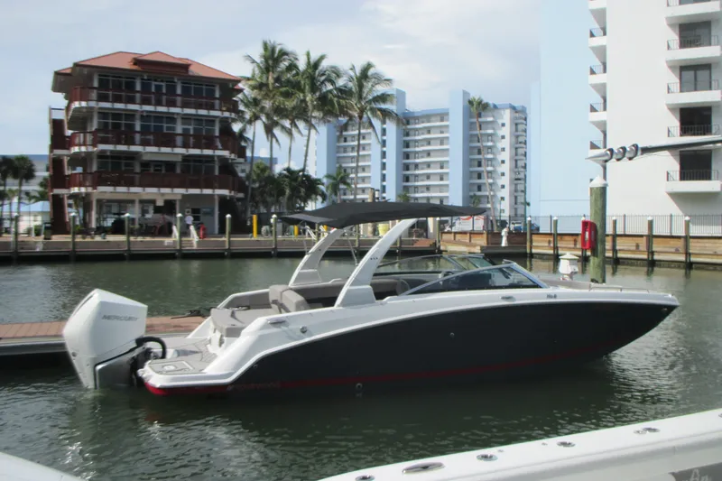 Slide: The Image of 2022 Four Winns HD8 OB boat docked in a marina with modern buildings in the background. - 1