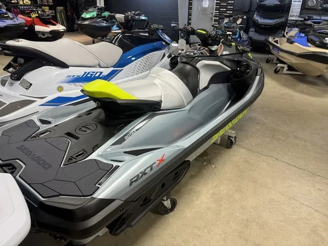 Slide: The Image of A 2026 Sea-Doo RXT-X jet ski in a showroom, surrounded by other personal watercraft. - 6