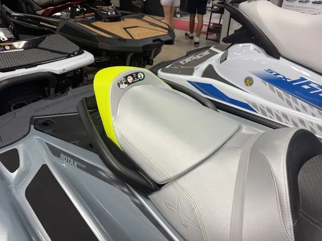 Slide: The Image of A Sea-Doo RXT-X jet ski with a gray and yellow seat, displayed in a showroom. - 11