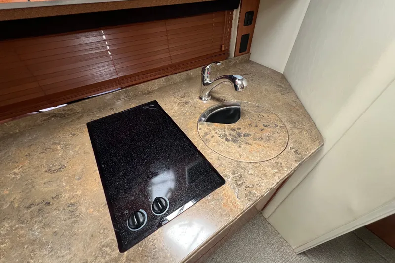 Slide: The Image of 2008 Cruisers Yachts 330 Express galley with stovetop and sink on marble countertop. - 28
