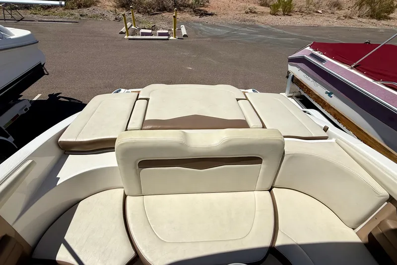 Slide: The Image of 2014 Chaparral 226 SSi boat interior with beige and brown seating, parked on asphalt. - 27