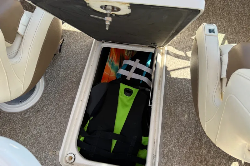 Slide: The Image of 2014 Chaparral 226 SSi boat storage compartment with life jacket and colorful items. - 34