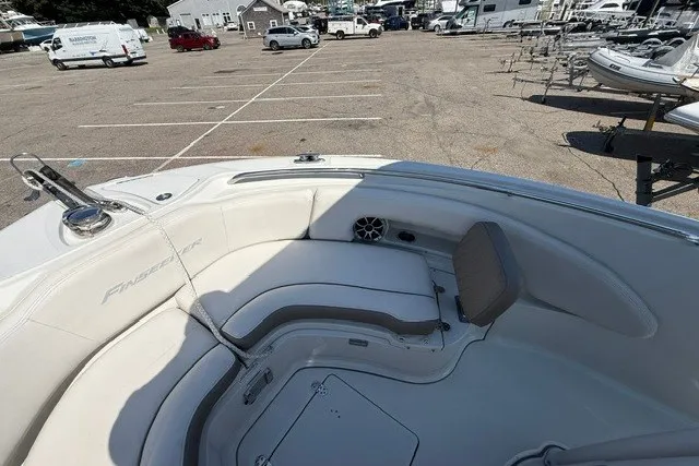 Slide: The Image of 2022 Finseeker 230 FS boat interior with seating, parked in a marina lot. - 17