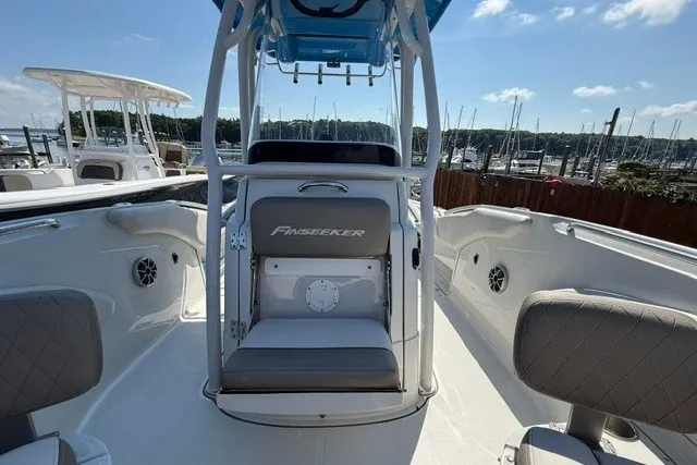 Slide: The Image of 2022 Finseeker 230 FS boat interior with seating and console, docked at marina. - 20
