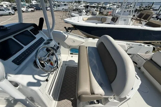 Slide: The Image of 2022 Finseeker 230 FS boat interior with steering wheel and seating at marina. - 14