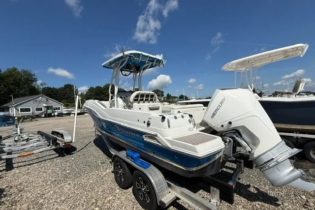 Slide: The Image of 2022 Finseeker 230 FS boat on trailer with Mercury engine, parked outdoors under blue sky. - 5