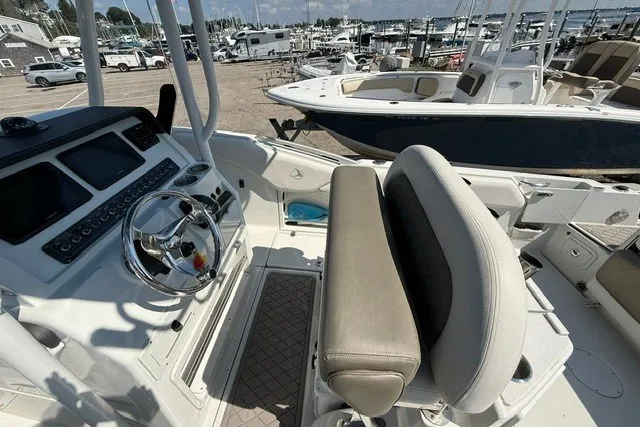 Slide: The Image of 2022 Finseeker 230 FS boat interior with steering wheel and seating at marina. - 13
