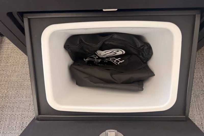 Slide: The Image of Storage compartment in a 2025 Barletta Cabrio 24UE boat with a black bag inside. - 28