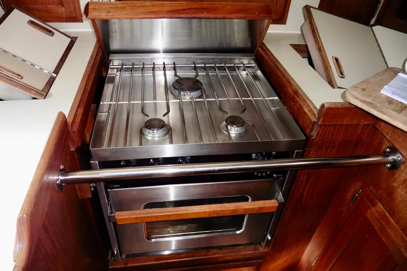 Slide: The Image of 1986 Ericson 35.3 yacht kitchen with stainless steel stove and wooden cabinetry. - 32