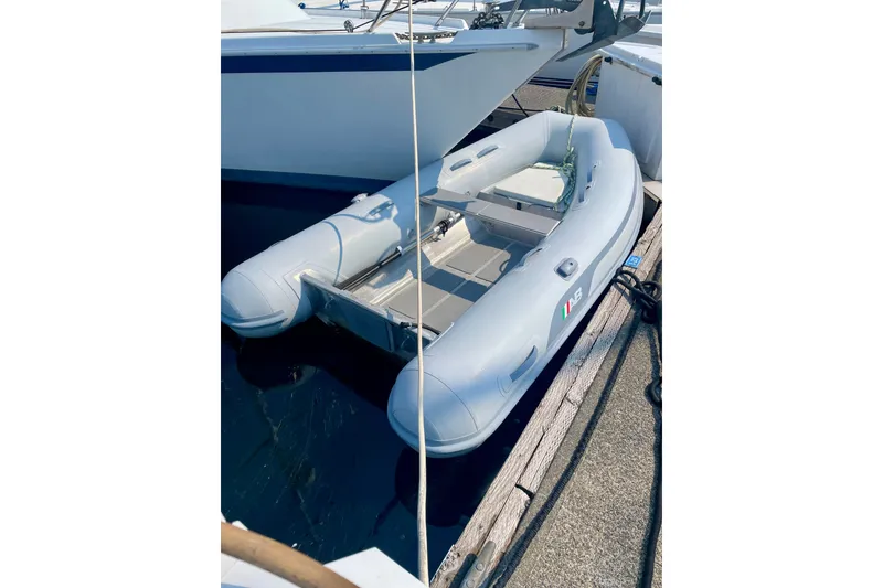 Slide: The Image of Inflatable dinghy docked beside Ericson 35.3 sailboat, 1986 model, in a marina setting. - 11