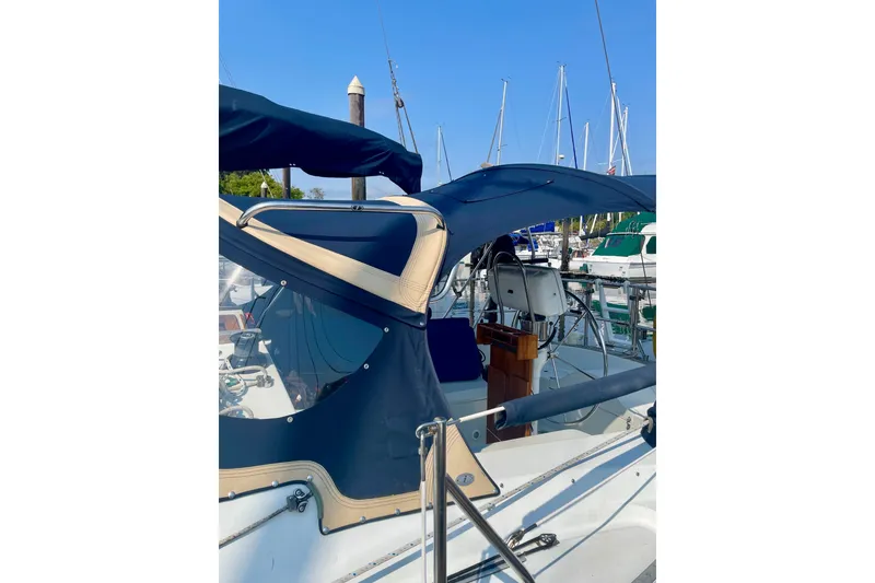 Slide: The Image of 1986 Ericson 35.3 sailboat with blue canvas cover docked at marina. - 6