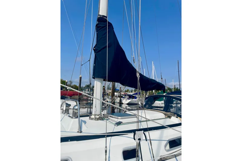 Slide: The Image of 1986 Ericson 35.3 sailboat with covered mainsail, docked in a marina under clear blue sky. - 3