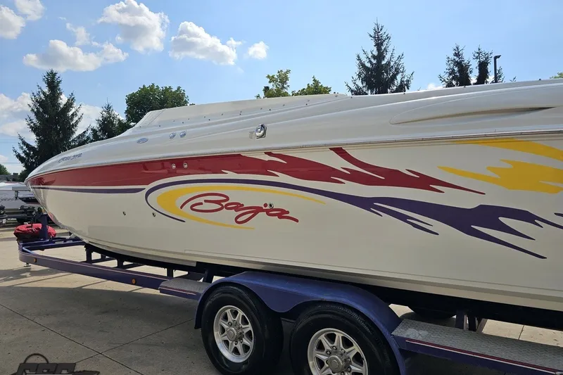 Slide: The Image of 2003 Baja 342 speedboat with colorful graphics on a trailer under a blue sky. - 24