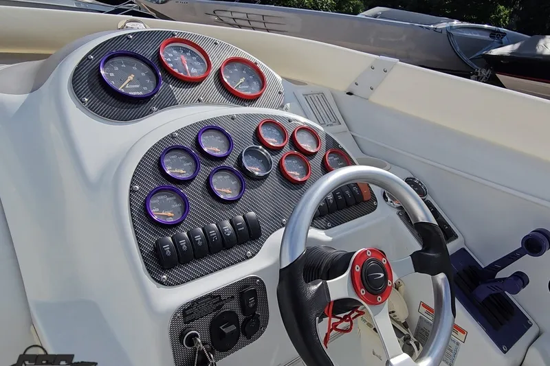 Slide: The Image of Dashboard of a 2003 Baja 342 boat with gauges and steering wheel. - 49