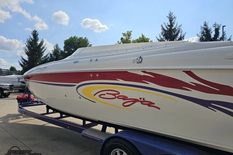 Slide: The Image of 2003 Baja 342 speedboat with vibrant graphics on a trailer, under a clear blue sky. - 23