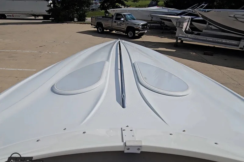 Slide: The Image of 2003 Baja 342 boat bow view in a marina with parked vehicles and boats. - 57