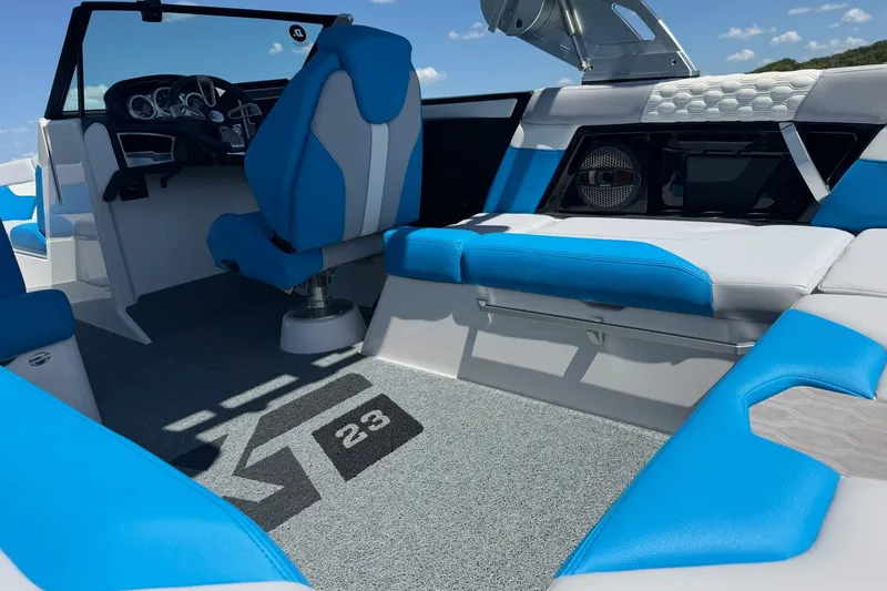 Slide: The Image of 2023 MasterCraft XT23 boat interior with blue and white seating, modern dashboard, and logo carpet. - 21