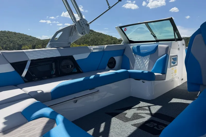 Slide: The Image of 2023 MasterCraft XT23 boat interior with blue and white seating, under a clear sky. - 22