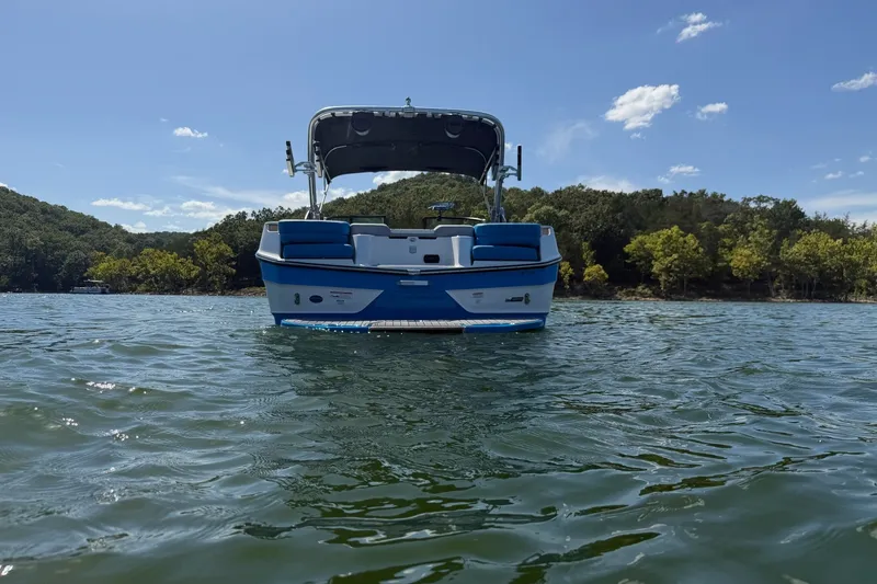 Slide: The Image of 2023 MasterCraft XT23 boat on a scenic lake with lush green hills. - 39